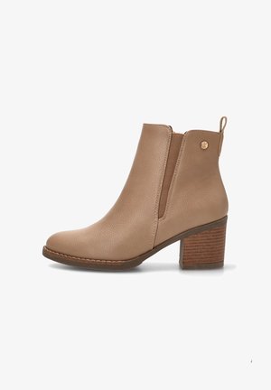 Botas de tobillo beige hechas de cuero texturizado con paneles elásticos y un tacón de madera apilada. Presenta un pequeño detalle de logo y acentos de costura.
