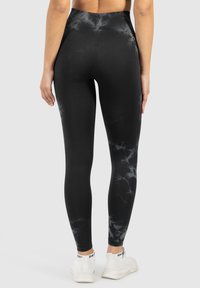 Leggings neri a vita alta realizzati in un tessuto elasticizzato, con un sottile motivo marmorizzato grigio e una superficie liscia che si adatta al corpo.