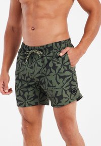 Kupaći šorts u kamuflažnom uzorku s listovima u tamnozelenoj i crnoj boji, s elastičnom tregerskom trakom i bočnim džepovima. Teksturalna tkanina.