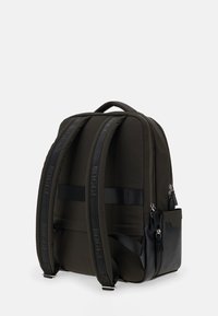 Zwarte en olijfgroene rugzak van nylon en leer. Bevat gewatteerde schouderbanden, ritsvakken en logodetails.