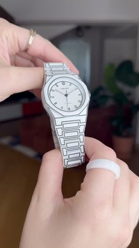 Witte horloge met een ronde wijzerplaat, zilverkleurige uurmarkeringen en een geometrische schakelarmband met zwarte accenten. Merknnaam op de wijzerplaat.