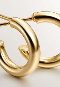 Aretes de aro de oro con una superficie lisa y pulida y un diseño curvado y sin costuras. Asegurados con un cierre de poste delgado.