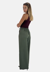 Groene wijde broek met een elastische tailleband, gecombineerd met een aansluitend bordeauxrood tanktop. Glad textuur, minimalistisch ontwerp en geen zichtbare patronen.