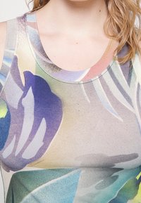 Top bez rękawów z kolorowym wzorem kwiatowym w odcieniach purpury, niebieskiego i zielonego. Miękka, elastyczna tkanina z okrągłym dekoltem i delikatną teksturą.