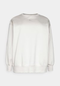 Vit sweatshirt med rund halsringning, långa ärmar och elastiska muddar. Har en liten svart logotyp på bröstet och ett mjukt, texturerat tyg.
