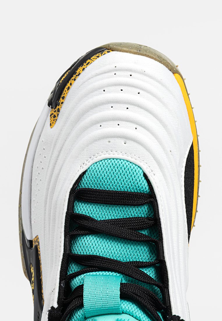 Zapatilla blanca con diseño texturizado y ondulado; acentos en negro y amarillo. Cordones azul claro y lengüeta de malla. Suela transparente con detalles de agarre.