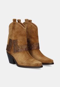 Botas de tobillo de ante marrón con punta afilada, que presentan una banda decorativa de strass en la parte trasera y un tacón apilado de altura media.