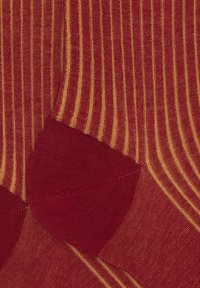 Rote Socken mit gelben Streifen, gestrickte Textur, verstärkte Ferse und Zehen, mit einer glatten Oberfläche und präzisen, gleichmäßig verteilten Linien.