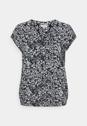 Blouse noire à manches courtes avec imprimé floral blanc et col en V, étiquette de taille visible à l'encolure.