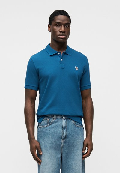 Polo à manches courtes en coton bleu vif avec col, patte de boutonnage à deux boutons et logo d'ours brodé sur la poitrine gauche.