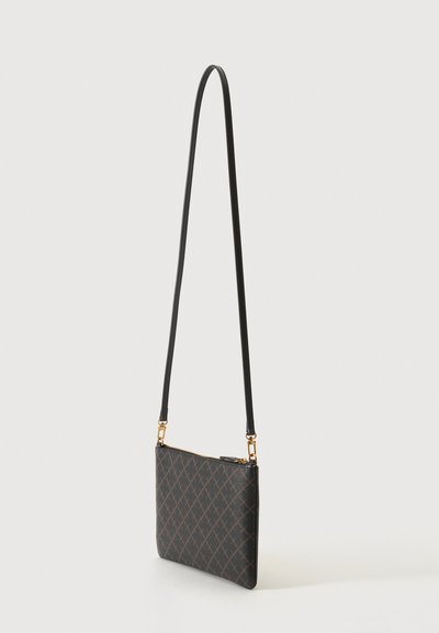 Petit sac bandoulière noir avec une fine lanière, des ferrures dorées et un motif discret en losanges marron, suspendu devant un fond uni.
