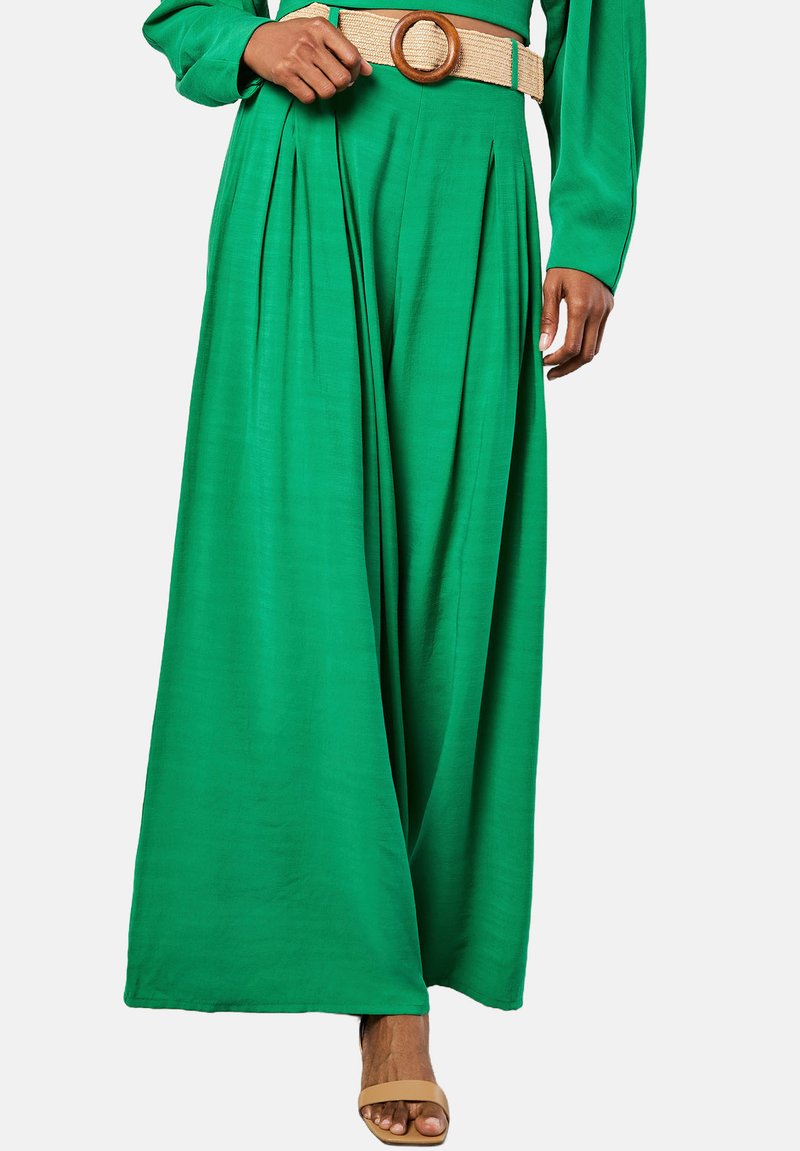 Groene, wijde broek met plooien, gemaakt van een lichtgewicht stof. Gecombineerd met een beige geweven riem met een ronde gesp.