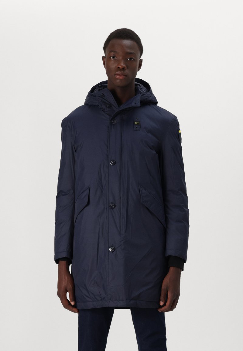 Navy puffer jacket with a hood, featuring a front button closure, two side pockets, and a textured, water-resistant fabric.