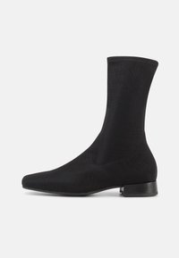 Μαύρο μποτάκι αστραγάλου με λείο, ελαστικό ύφασμα στον κορυφαίο μέρος και χαμηλό, στρωμένο τακούνι. Διαθέτει μ υτερή μύτη και αδιάκοπο σχέδιο.