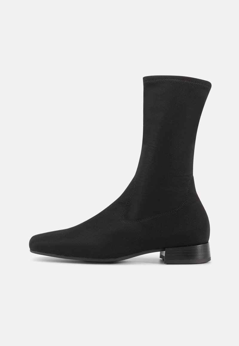 Μαύρο μποτάκι αστραγάλου με λείο, ελαστικό ύφασμα στον κορυφαίο μέρος και χαμηλό, στρωμένο τακούνι. Διαθέτει μυτερή μύτη και αδιάκοπο σχέδιο.