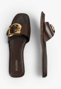 Brune lædersandaler med en bred strop og store guldbuckle-detaljer, flad sål og glat tekstur. Brandet er synligt på indersålen.