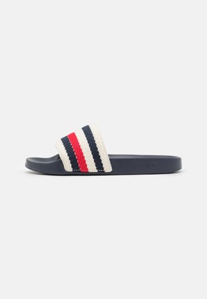 Enkelt navy slip-sandal med en hvid rem med teksturerede røde og navy diagonale striber på en ensfarvet baggrund.