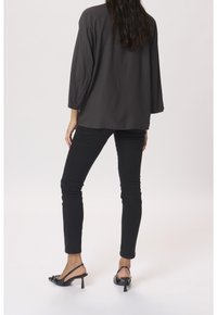 Tmavě šedá strukturovaná blůza s tříčtvrtečními rukávy, spárovaná s černými skinny džínami a černými lodičkami na podpatku.