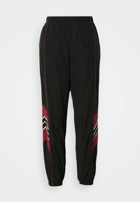 Pantalons de sport noirs avec une taille élastique, présentant des accents rouges et un motif en zigzag noir et blanc sur les côtés.