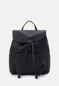 Mochila negra hecha de tela suave con cierre tipo solapa, bolsillo frontal con cremallera, detalle de cordón y acentos en tono dorado.