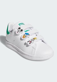 Sneakers bianchi in pelle con tre cinturini in velcro, caratterizzati dagli accenti dei personaggi di Topolino, Paperino e Pippo. Dettaglio verde sul tallone.