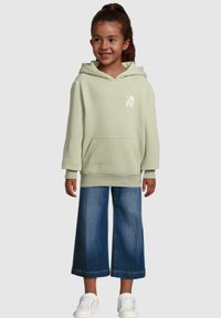 Light green hooded sweatshirt with a front pocket and white butterfly graphic, paired with wide-leg denim pants and white sneakers.