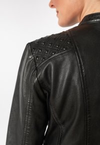 Schwarze Lederjacke mit rautenförmig strukturierten Schultern und glattem Körper, mit sichtbaren Nähten entlang der Nähte.