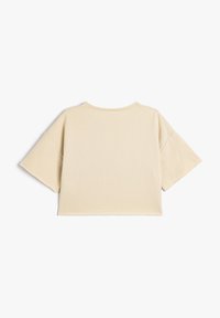 Camiseta beige corta con mangas cortas y anchas y un escote redondeado. Hecha de una suave tela de algodón, con dobladillos limpios y cosidos.