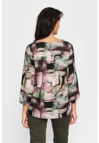 Bagudsigt af en let bluse med et pink, grønt og sort abstrakt mønster, der har 3/4 ærmer og en rund halsudskæring.