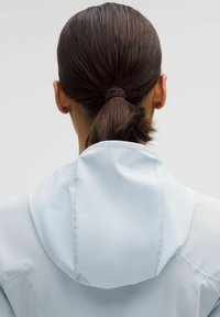 Light blue hooded jacket with a smooth texture, visible seam details, and a fitted design, seen from the back with hair tied in a ponytail.
