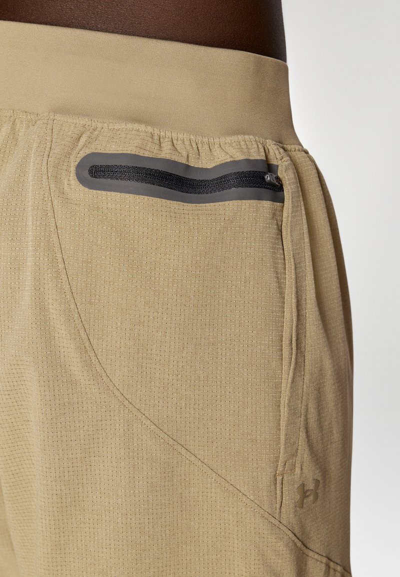 Beige Sportshorts mit strukturierter Oberfläche. Mit elastischem Bund und einer Reißverschlusstasche in schwarzem Rahmen. Logo in der unteren Ecke.