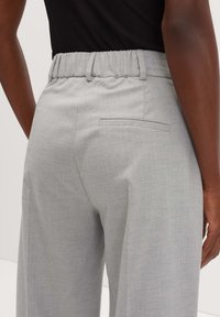 Pantaloni grigi su misura con una consistenza morbida, vita elastica e una tasca posteriore singola, mostrati dalla vista posteriore.