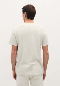 Lichtgrijze t-shirt met korte mouwen en een ronde hals. De stof heeft een subtiele textuur en een ontspannen pasvorm. Eenvoudig ontwerp, geen zichtbare patronen of accenten.