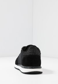 Black athletic shoe with a textured leather accent, mesh fabric, and a white speckled sole. Features a padded collar for comfort.