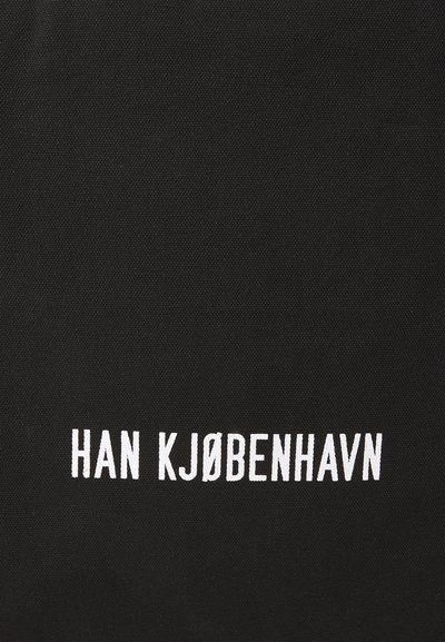 Črna platnena torba z izrazitim belim napisom "HAN KJØBENHAVN" v velikih črkah, ki poudarja minimalističen dizajn.