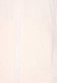 Felpa con zip di color pesca chiaro, con una texture liscia, dotata di una zip centrale, tessuto morbido e un design minimalista senza decorazioni.