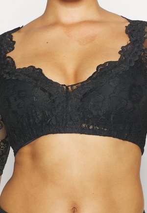 Haut court en dentelle noire à motifs floraux, porté, montrant le torse supérieur et le ventre.