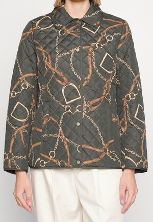 Sort quiltet jakke med print af guldkæde og brunt læderrem, med trykknapper og en klassisk krave, båret med hvide bukser.