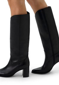 Black leather knee-high boots with a smooth texture, square block heel, and side zipper. Pointed toe and contoured upper design.