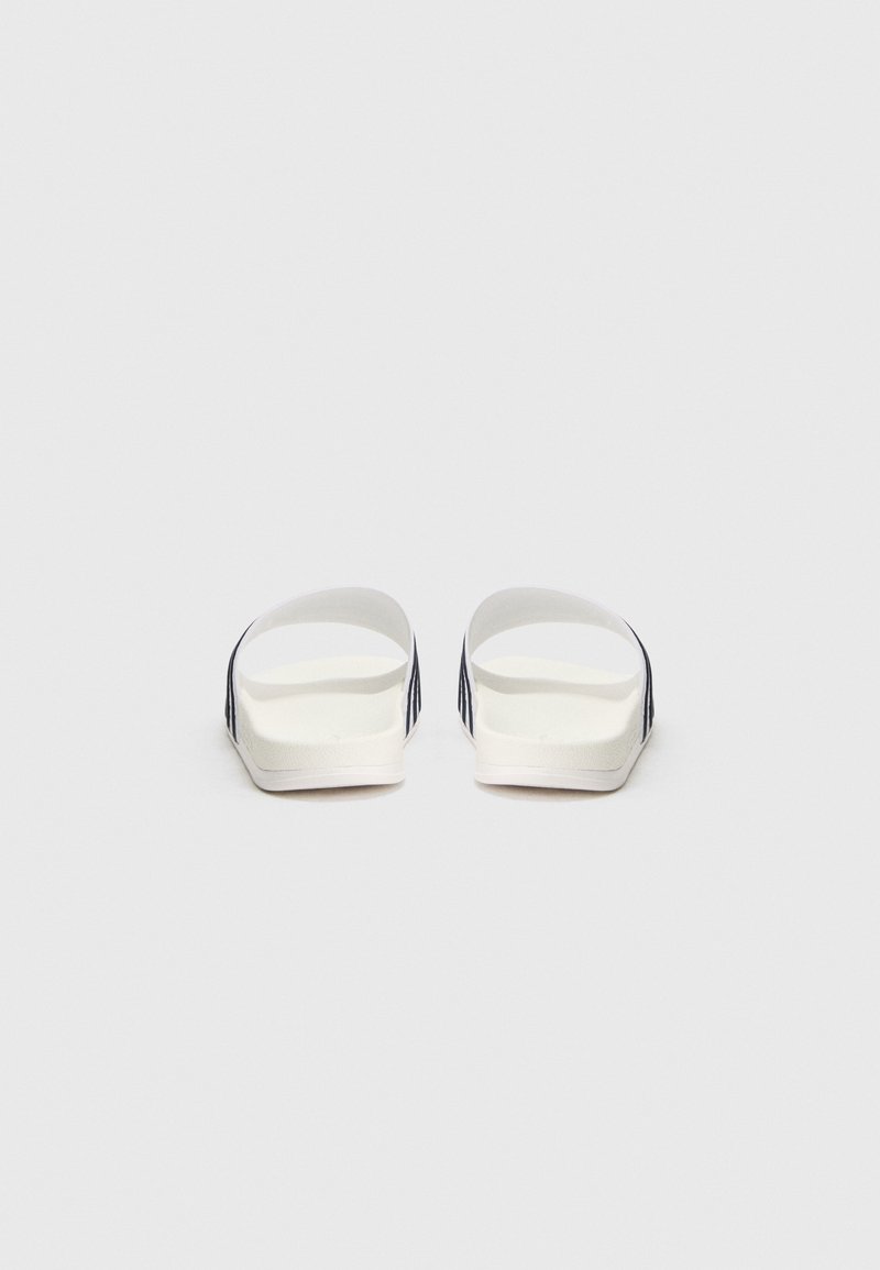 Sandali bianchi a fascia con una soletta liscia e testurizzata e punta aperta. Presentano strisce blu navy a contrasto sui lati.