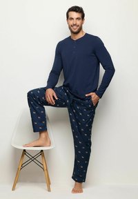 Camisa henley de manga larga en color navy combinada con pantalones de pijama estampados que presentan pequeñas ilustraciones de perros. Los pantalones cuentan con una cintura elástica y piernas rectas.