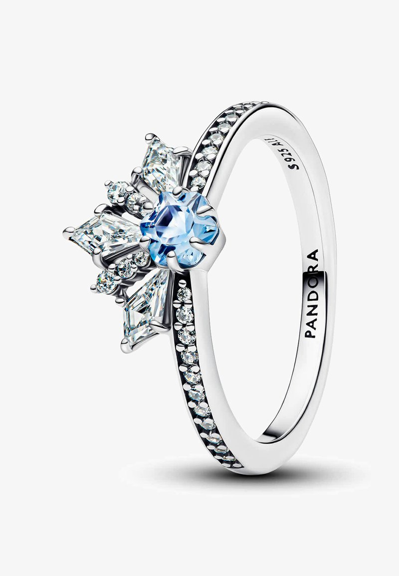 Anello d'argento con una pietra centrale di un blu chiaro circondata da pietre trasparenti. Ha un design a scallop e una banda liscia con piccoli dettagli.