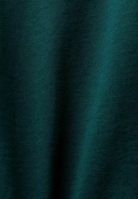 Dunkeltürkiser Stoff mit einer glatten Textur und einer leicht gebürsteten Oberfläche, die das Licht dezent reflektiert und weiche Schatten erzeugt.