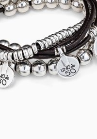 Pulsera de cuentas plateadas que presenta cuentas metálicas redondas y en espiral, intercaladas con tiras de cuero y etiquetas metálicas grabadas.