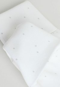 Biele ponožky z textúrovaného materiálu s malými sivými bodkami, so skladačným dizajnom pre ľahké uloženie.