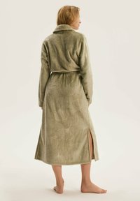 Długa oliwkowo-zielona szlafrok z teksturowanym wzorem liści, z kołnierzem typu szal oraz bocznymi rozporkami, wykonany z miękkiego materiału dla komfortu.