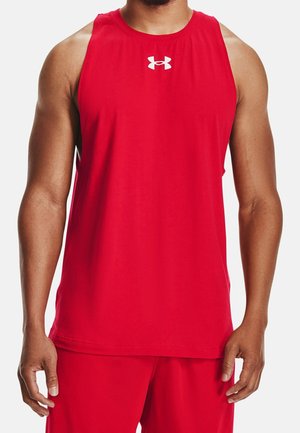 Man wearing sleeveless red athletic shirt and matching shorts with white Under Armour logo on chest, standing still.