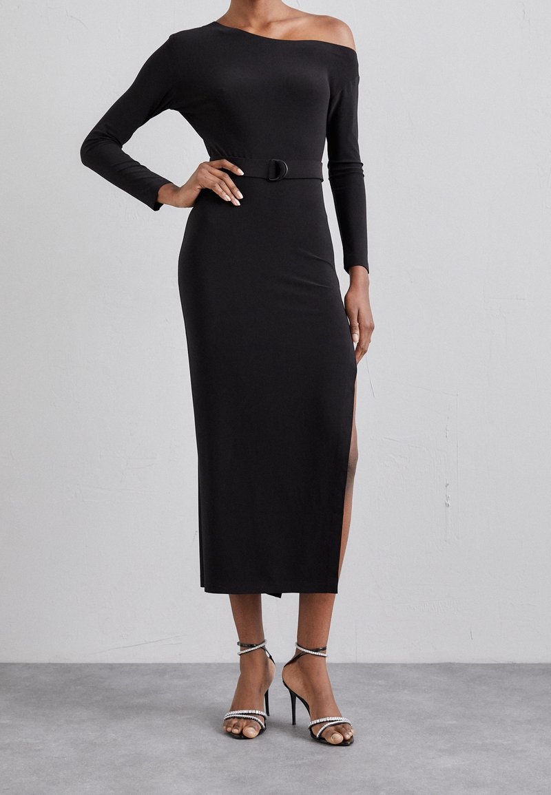 Czarna sukienka off-the-shoulder z długimi rękawami, dopasowaną sylwetką, bocznym rozcięciem oraz detalem w pasie w postaci paska. Gładka tekstura materiału.