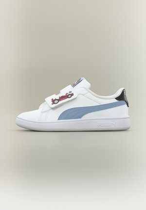 Baskets blanches Puma avec bande bleue, languette de talon noire et bride à velcro avec un motif graphique d’une voiture de course rouge et des drapeaux de course.