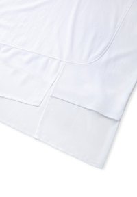 Top de algodón blanco, ligero, con escote redondeado, dobladillo curvado y diseño en capas con una textura suave.